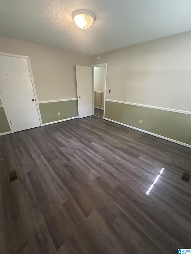 empty room with visible vents, dark wood-style flooring, and baseboards