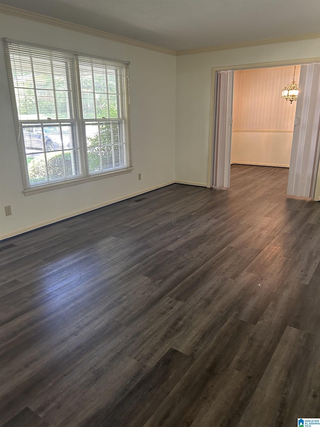 spare room with a notable chandelier, baseboards, ornamental molding, dark wood finished floors, and visible vents