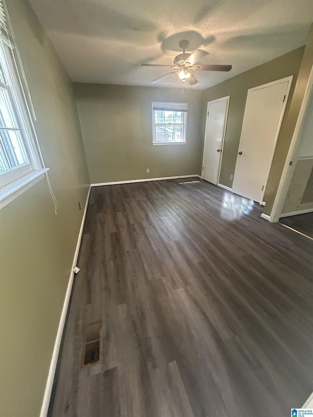 unfurnished bedroom with dark wood-style flooring, baseboards, ceiling fan, and visible vents
