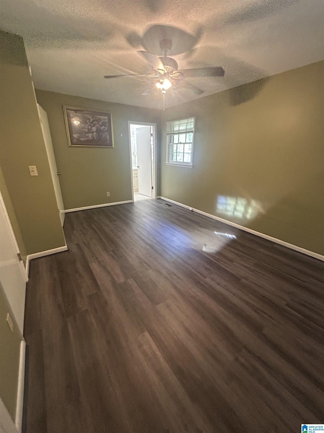 empty room featuring a ceiling fan, dark wood-style flooring, baseboards, and a textured ceiling