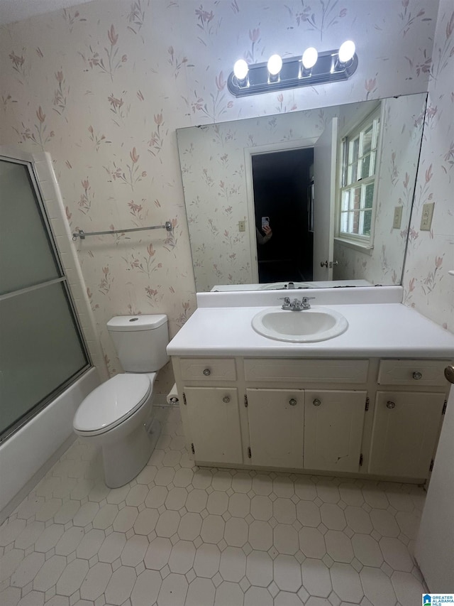 full bathroom featuring toilet, tile patterned floors, vanity, and wallpapered walls