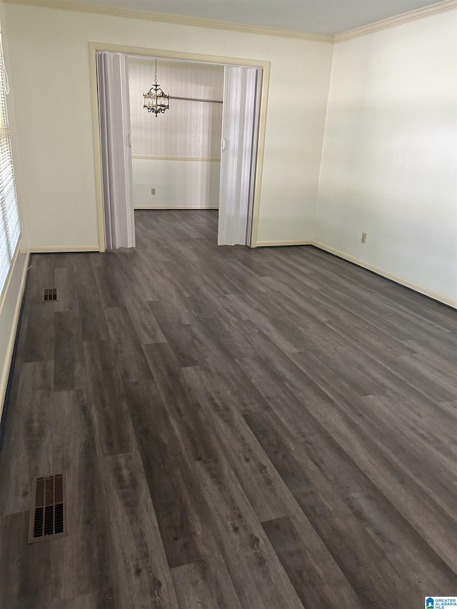 empty room with an inviting chandelier, visible vents, dark wood-style flooring, and crown molding