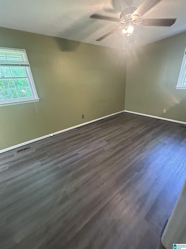spare room with baseboards, ceiling fan, visible vents, and dark wood-style flooring