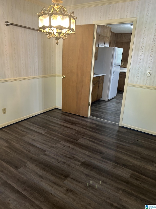 unfurnished dining area with wallpapered walls, dark wood-style floors, and a notable chandelier