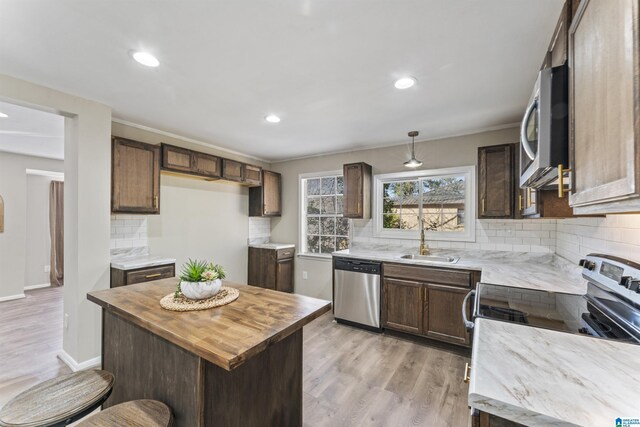 kitchen featuring a sink, stainless steel appliances, butcher block counters, backsplash, and light wood-style floors