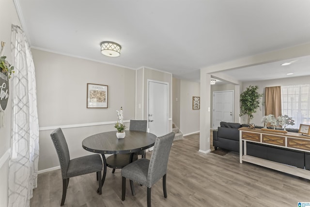 dining room with baseboards, stairway, ornamental molding, and wood finished floors