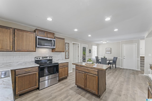 kitchen with stainless steel appliances, tasteful backsplash, ornamental molding, light wood finished floors, and baseboards