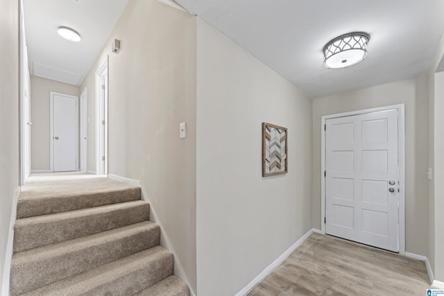 foyer entrance featuring light wood finished floors, stairs, and baseboards