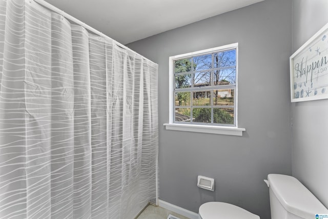 full bathroom featuring toilet, a shower with shower curtain, and baseboards