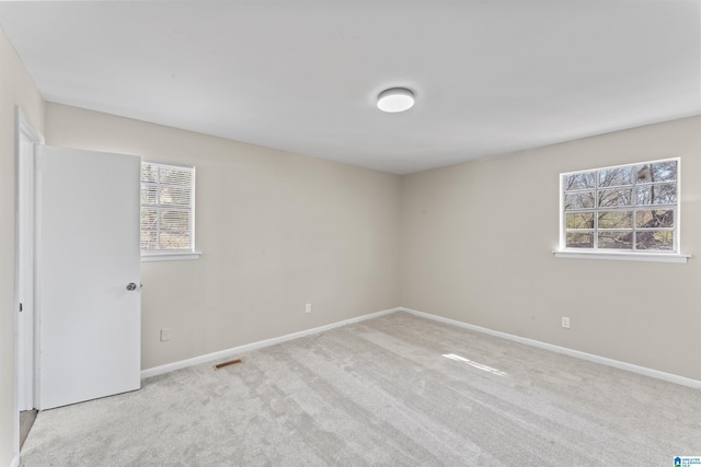 spare room featuring carpet flooring, visible vents, and baseboards