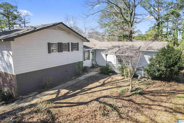split level home with central air condition unit and roof with shingles