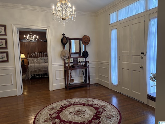 entrance foyer with a decorative wall, crown molding, a chandelier, and wood finished floors