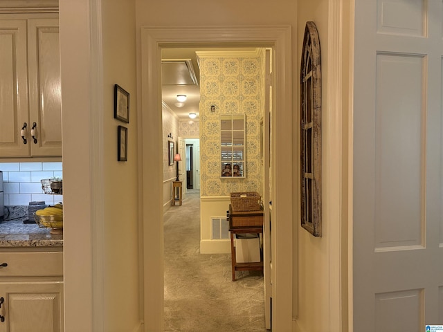 hall with light carpet, crown molding, and wallpapered walls