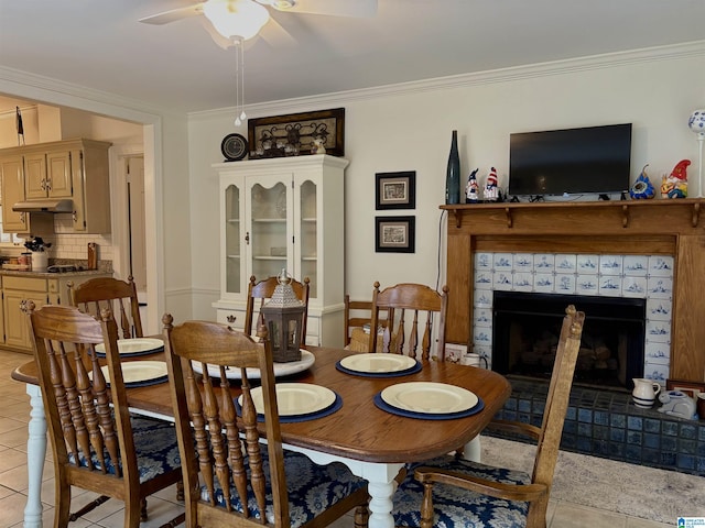 dining space with ornamental molding, light tile patterned floors, a fireplace, and ceiling fan