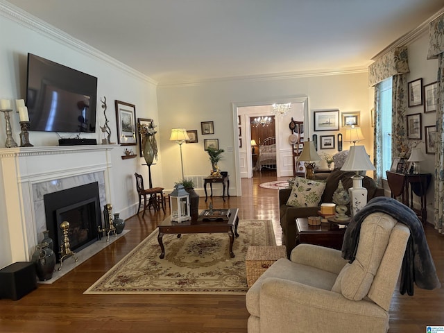 living area with a fireplace, crown molding, a chandelier, and wood finished floors