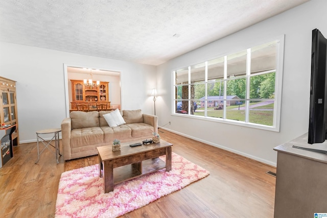 1111 Creek Trl, Anniston, AL 36206 - living room featuring a textured ceiling, baseboards, light wood-style flooring, and a notable chandelier