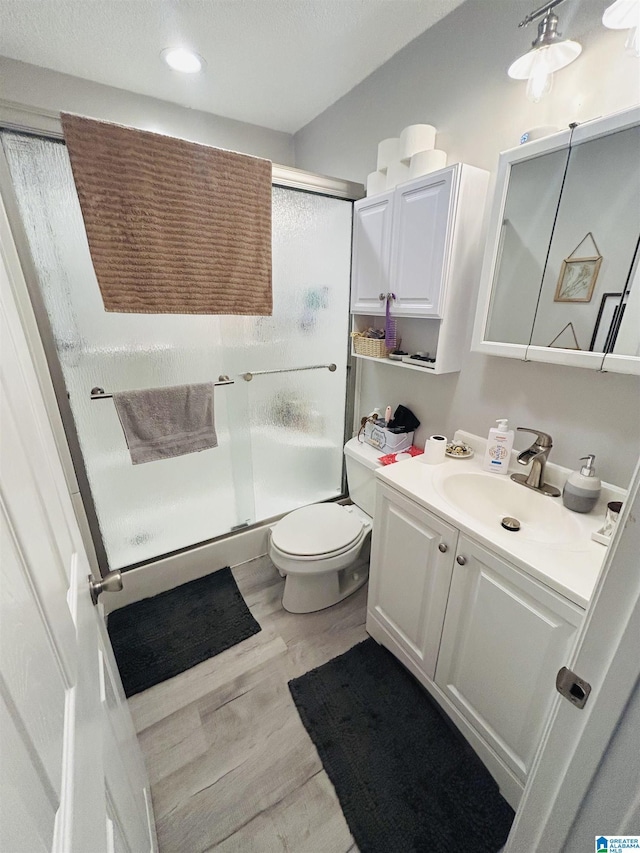 bathroom with vanity, wood finished floors, a stall shower, and toilet