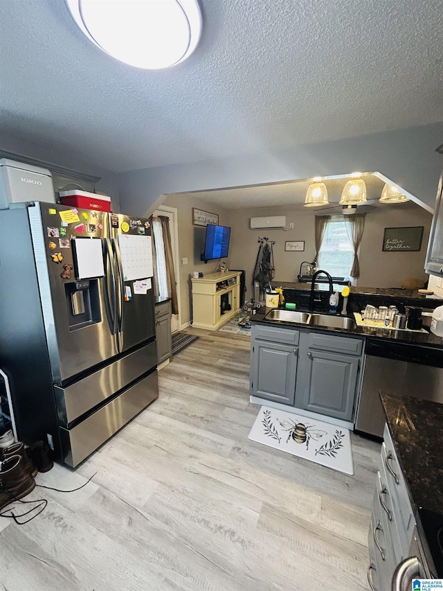 kitchen featuring a sink, a textured ceiling, light wood-style floors, and appliances with stainless steel finishes