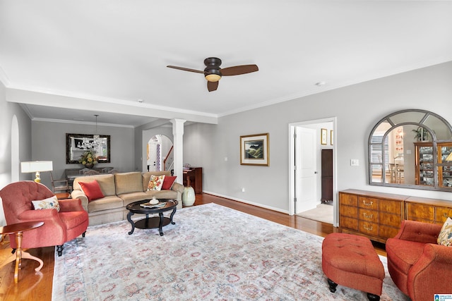 living room with decorative columns, wood finished floors, ceiling fan, ornamental molding, and baseboards