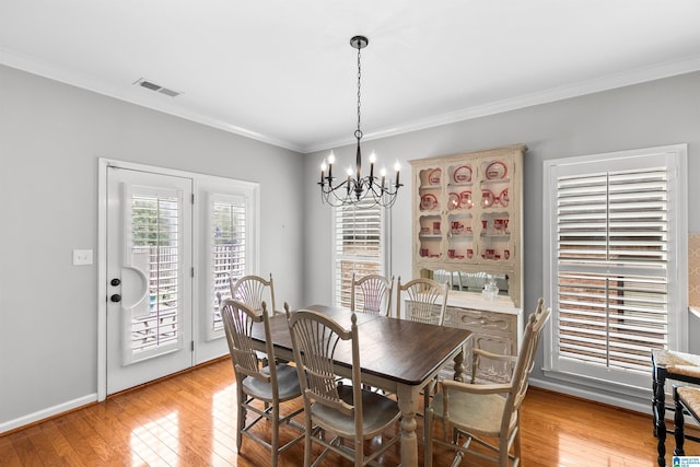 dining area with a chandelier, ornamental molding, light wood-style floors, and baseboards
