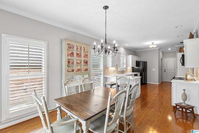 dining area with a chandelier, ornamental molding, light wood-style floors, recessed lighting, and baseboards