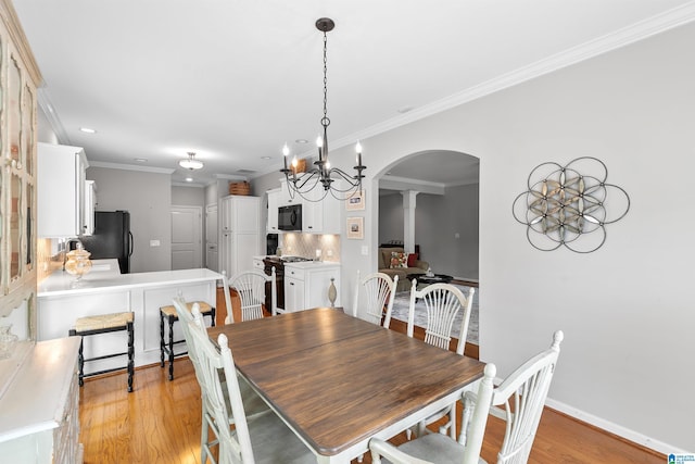 dining space with arched walkways, ornate columns, light wood-type flooring, ornamental molding, and baseboards