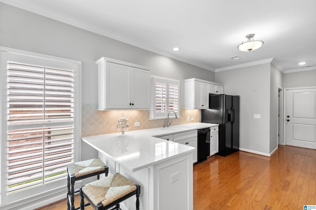 kitchen with black appliances, a sink, white cabinetry, a breakfast bar, and recessed lighting