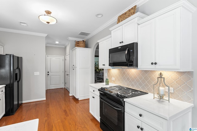 kitchen featuring black appliances, arched walkways, backsplash, light countertops, and white cabinets