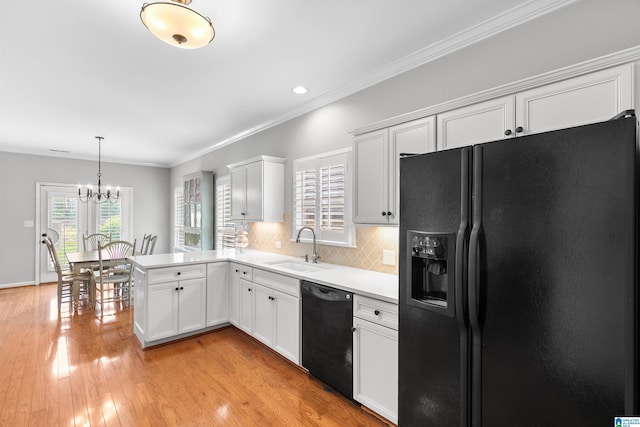 kitchen with black appliances, a sink, light countertops, a chandelier, and a peninsula