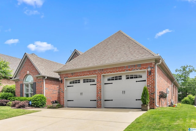 view of front facade featuring brick siding, roof with shingles, driveway, a front yard, and an attached garage