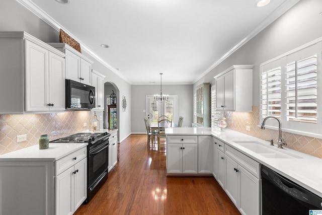 kitchen featuring black appliances, a sink, a chandelier, arched walkways, and light countertops