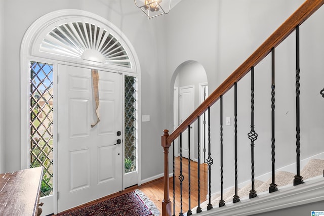 entryway with stairs, arched walkways, and wood finished floors