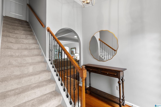 staircase with baseboards, arched walkways, and a chandelier