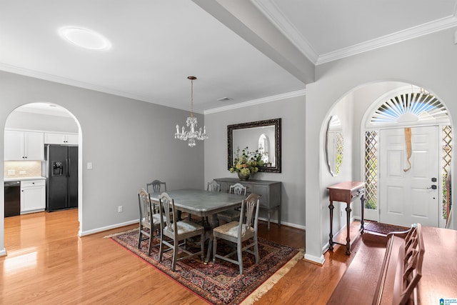 dining area with arched walkways, light wood-style flooring, crown molding, baseboards, and a chandelier