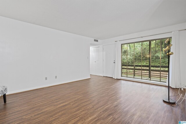 unfurnished living room featuring wood finished floors and baseboards