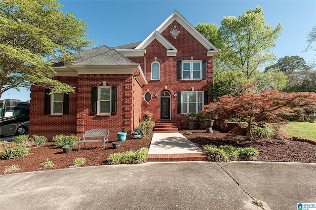 traditional-style house featuring a shingled roof and brick siding