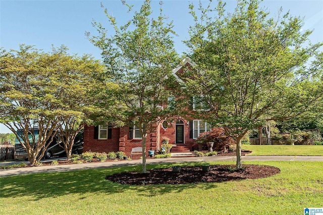 view of front of property featuring brick siding, curved driveway, and a front lawn
