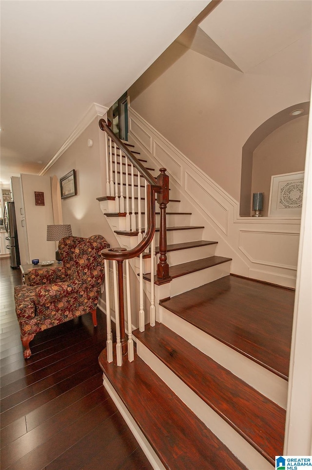 stairs with ornamental molding and hardwood / wood-style flooring