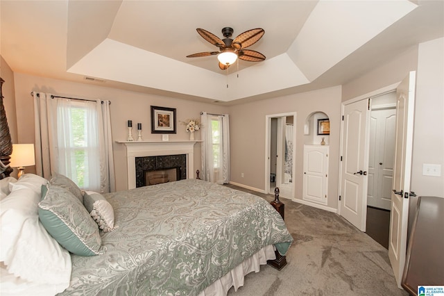 carpeted bedroom featuring a closet, visible vents, baseboards, a raised ceiling, and a high end fireplace