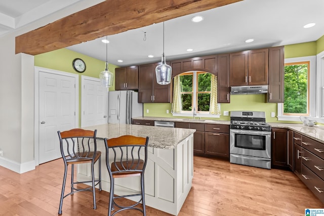 825 Dogwood Ln, Ashville, AL 35953 - kitchen with light wood-style flooring, stainless steel appliances, dark brown cabinetry, under cabinet range hood, and light stone counters
