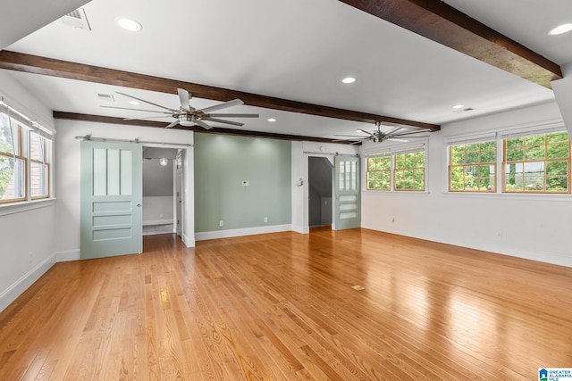 825 Dogwood Ln, Ashville, AL 35953 - unfurnished living room featuring light wood-type flooring, a barn door, a ceiling fan, and beam ceiling