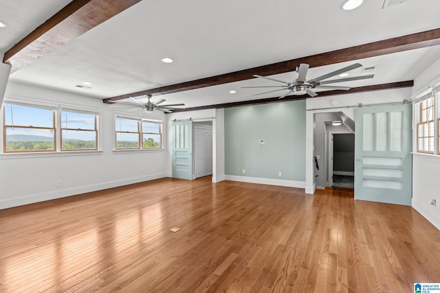 825 Dogwood Ln, Ashville, AL 35953 - unfurnished living room with ceiling fan, a healthy amount of sunlight, beam ceiling, and a barn door