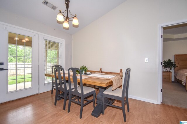 dining room featuring a chandelier, light wood-style flooring, baseboards, and lofted ceiling