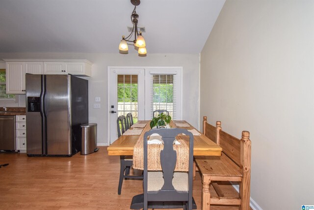 dining space with light wood-style flooring, baseboards, and a chandelier