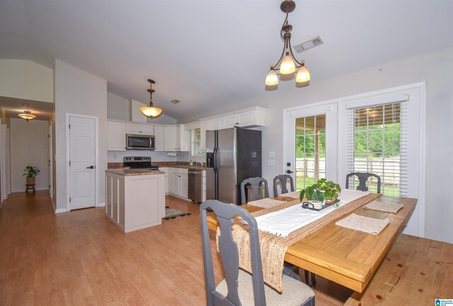dining space featuring lofted ceiling and light wood-type flooring