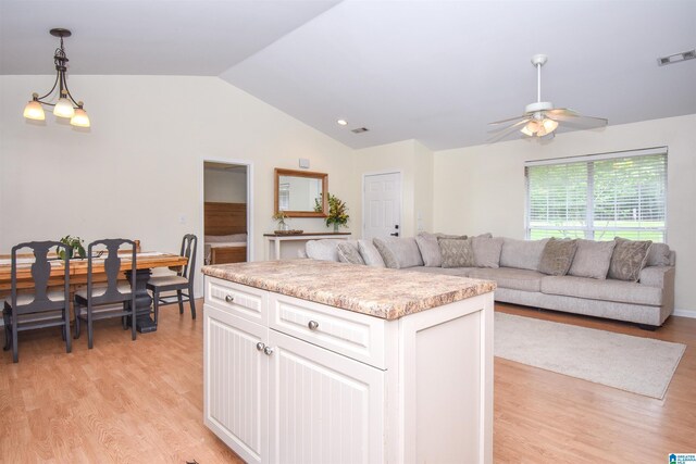 kitchen with vaulted ceiling, a kitchen island, light wood-type flooring, open floor plan, and a ceiling fan