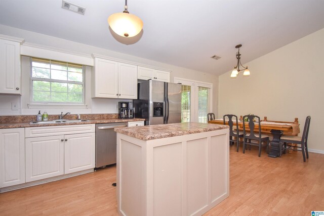 kitchen with stainless steel appliances, a sink, light wood-type flooring, a kitchen island, and vaulted ceiling