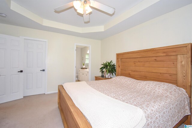 bedroom featuring a tray ceiling, light carpet, baseboards, and ceiling fan