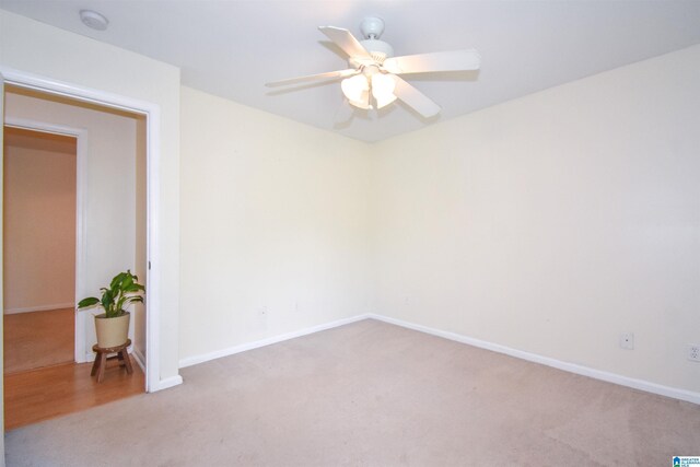 spare room featuring light colored carpet, ceiling fan, baseboards, and a smoke detector