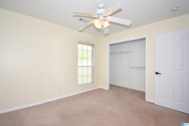 unfurnished bedroom with light colored carpet, a closet, baseboards, and a ceiling fan